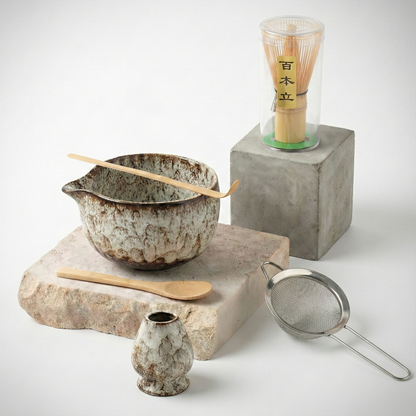Kit matcha complet avec bol à bec verseur en céramique blanche mouchetée style pierre, accompagné de son porte-fouet assorti et des accessoires en bambou.