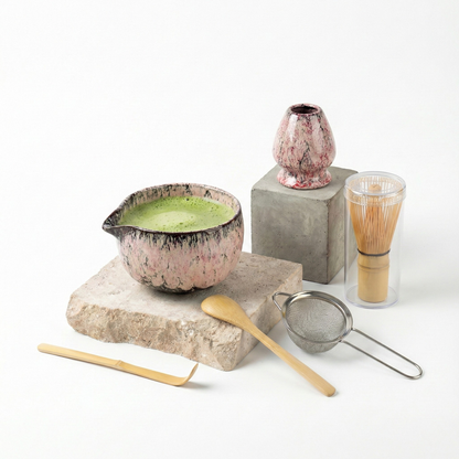 Kit de préparation matcha avec un bol à bec verseur et un support de fouet en céramique rose marbré de touches sombres, pour une esthétique douce et moderne.