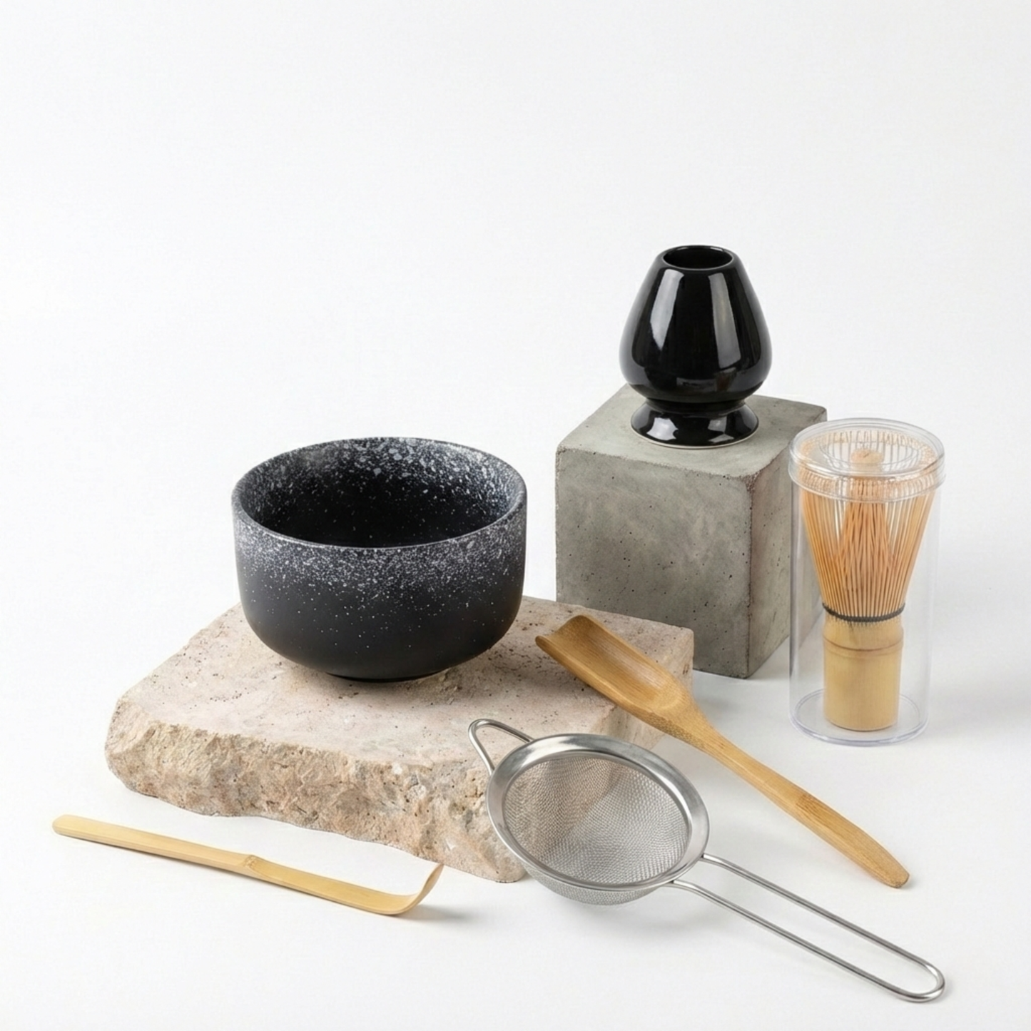 Set complet matcha avec un bol noir profond moucheté de blanc (style pierre de lave ou galaxie) et ses accessoires en bambou, offrant un contraste visuel saisissant avec la poudre verte.