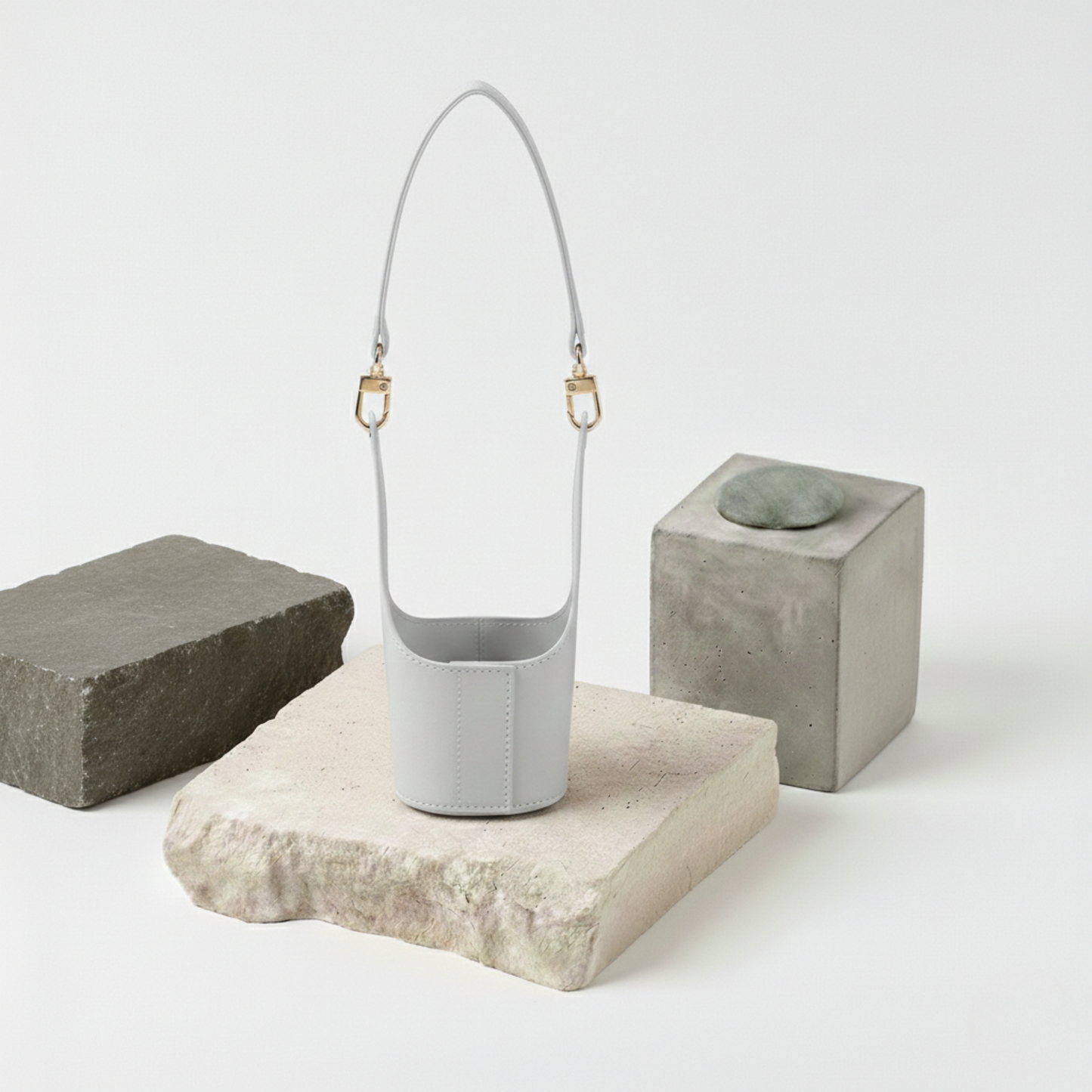 Porte-cup couleur gris doux (Light Grey) en matière végane déperlante, posé sur un support en pierre, alliant design épuré moderne et facilité d'entretien.