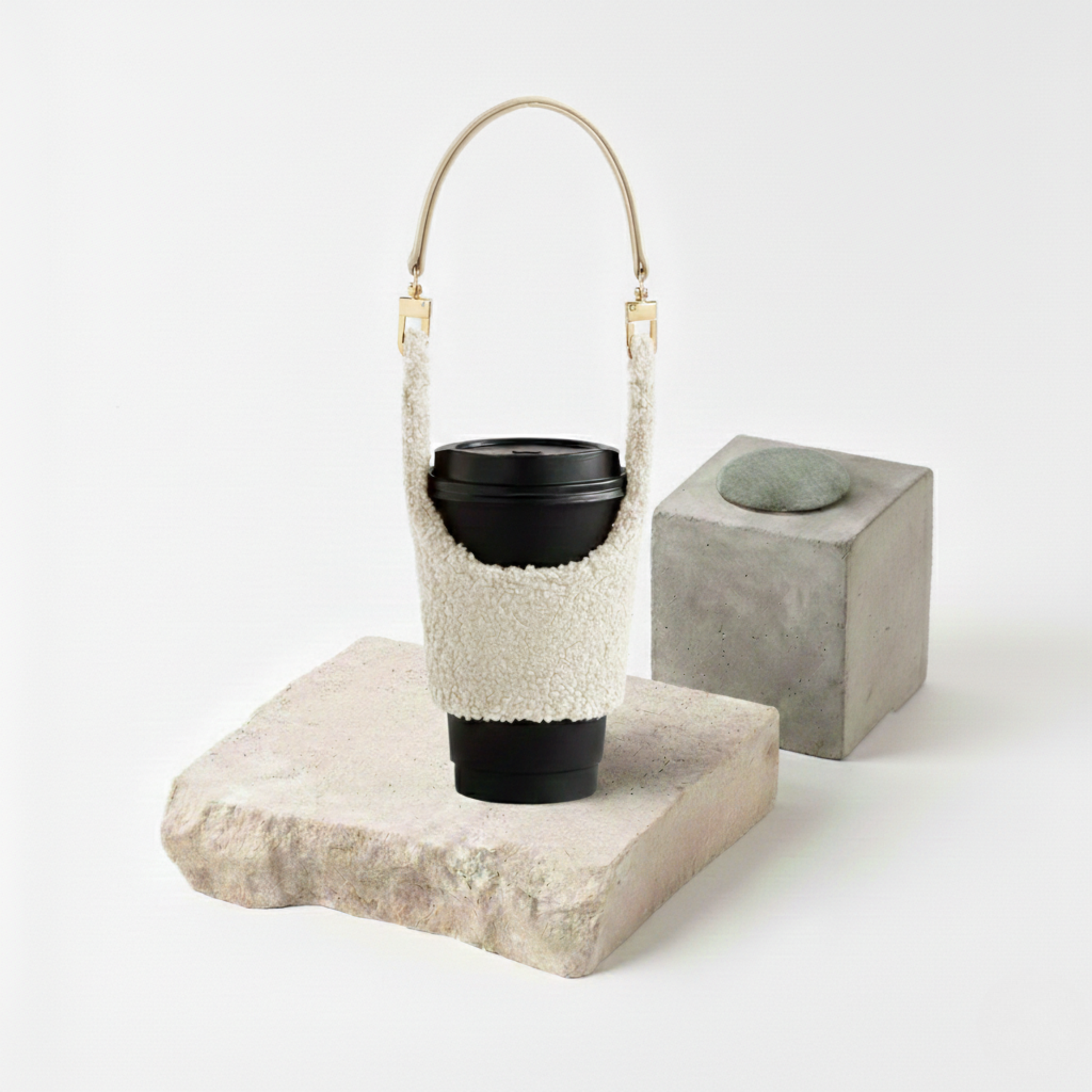 Manchon isolant pour gobelet en tissu pelucheux blanc crème (texture mouton/sherpa) avec une anse dorée élégante, transformant votre boisson en accessoire de mode hivernal.