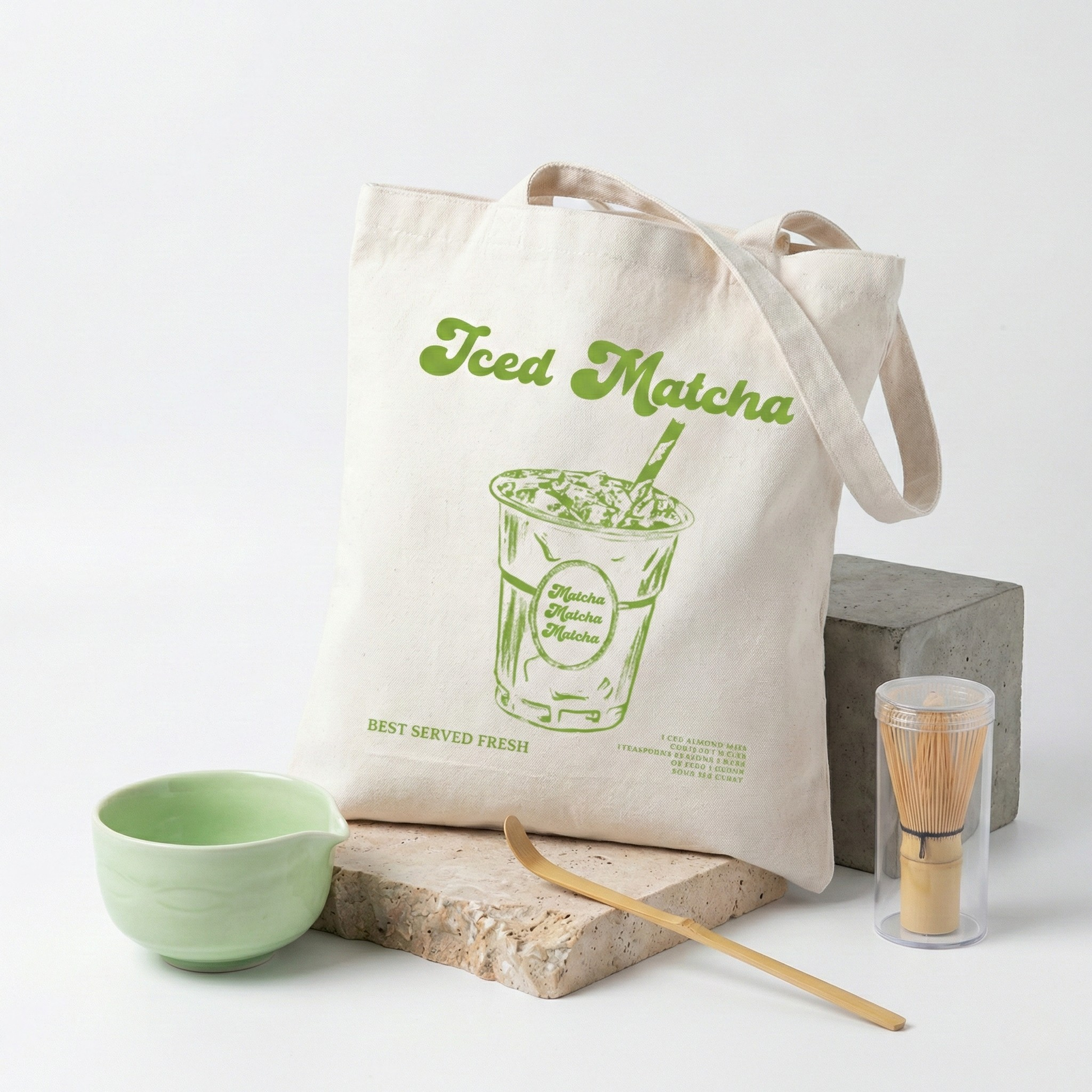 Sac tote bag en coton canvas beige avec une illustration rétro d'un Iced Matcha vert, posé sur une pierre décorative, idéal pour les courses zéro déchet.