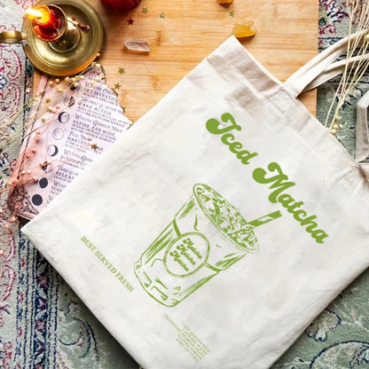Sac tote bag en coton canvas beige avec une illustration rétro d'un Iced Matcha vert, posé sur un tapis, idéal pour les courses zéro déchet.