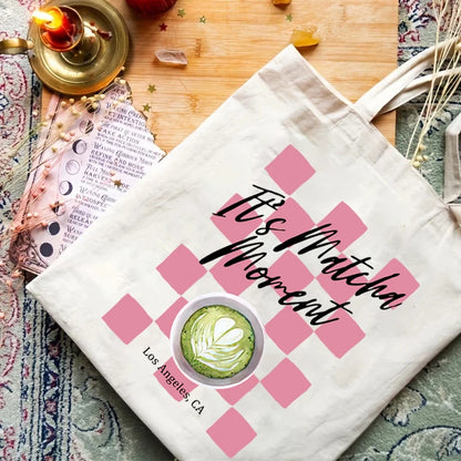 Sac fourre-tout tendance avec motif damier rose déstructuré et calligraphie "It's Matcha Moment", inspiré du style des coffee shops californiens.