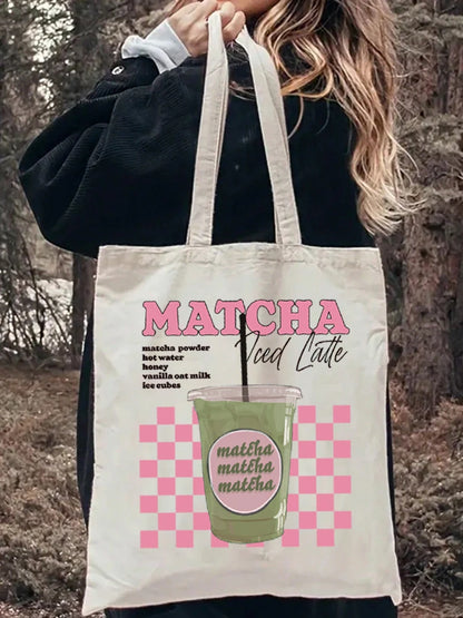Tote bag porté à l'épaule sur une tenue en jean, affichant un design esthétique rose à damier (checkerboard) avec l'inscription Matcha Iced Latte.