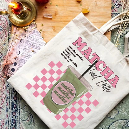Tote bag porté à l'épaule sur une tenue en jean, affichant un design esthétique rose à damier (checkerboard) avec l'inscription Matcha Iced Latte.